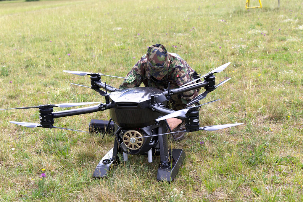 Eine Person bereitet eine Transportdrohne auf einem Feld für eine Cargo-Mission vor.