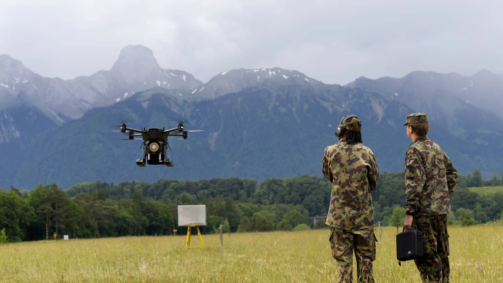 Zwei Angehörige der Armee beobachten eine Transportdrohne während eines Testflugs auf einem Übungsgelände.