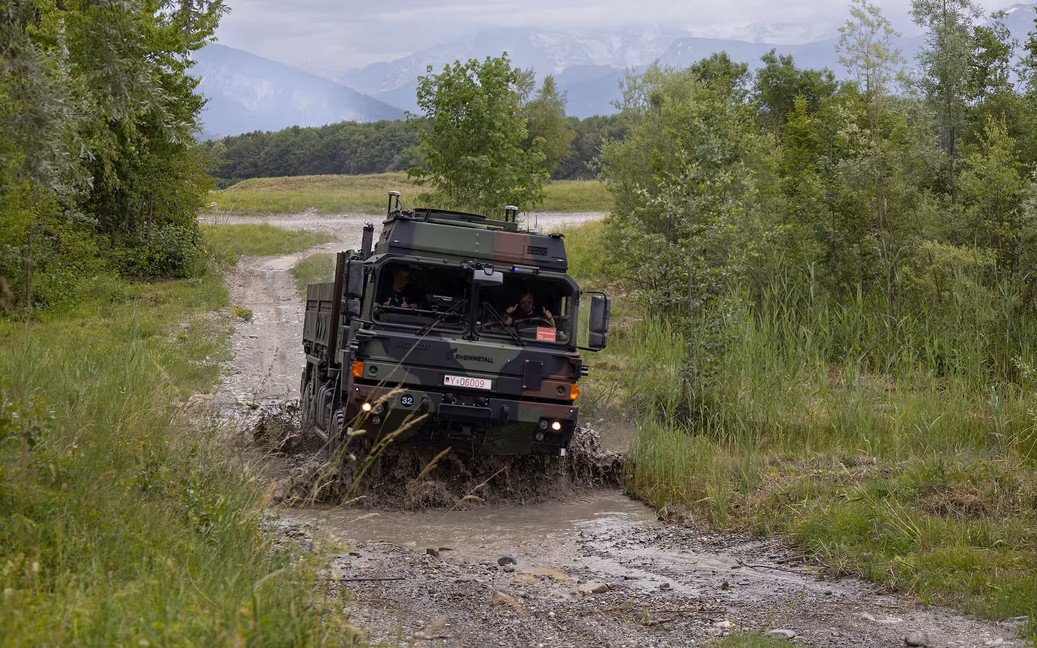 Photo d'un véhicule militaire traversant un tronçon inondé d'un chemin de terre.