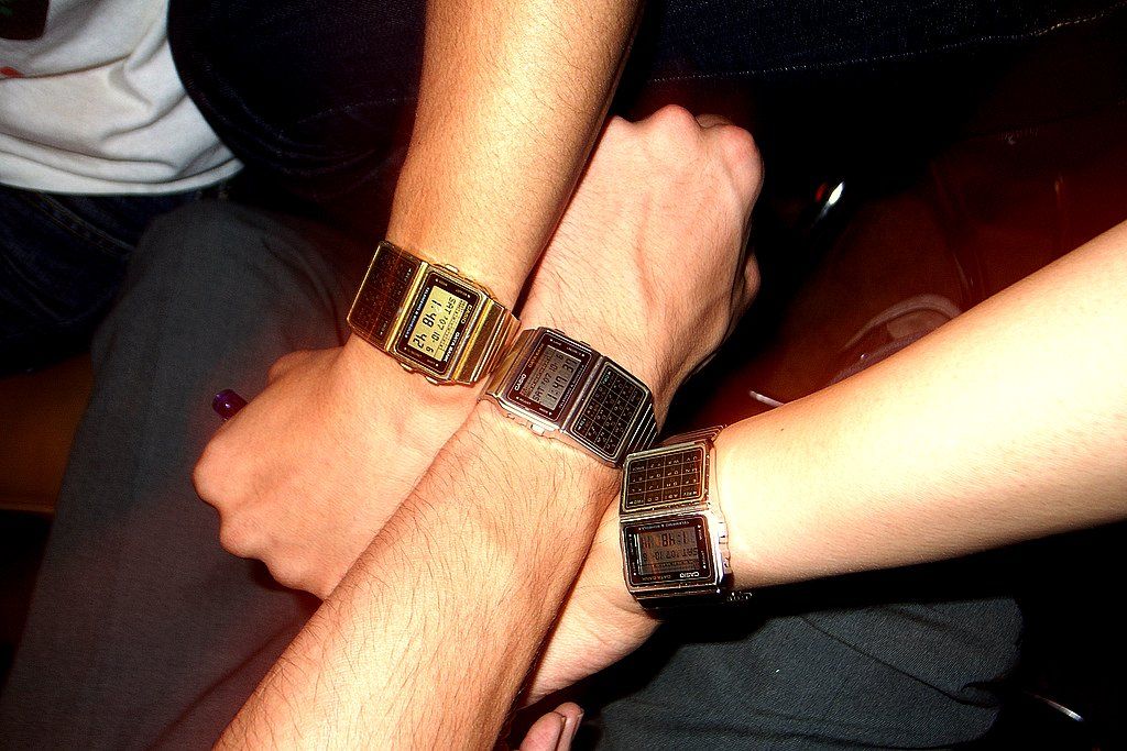 Trois poignets avec la même montre numérique, mais avec une heure légèrement différente. La synchronisation horaire se fait souvent en arrière-plan, sans que l'on s'en rende compte. Selon la méthode de mesure, les indications de temps sont plus ou moins précises et ne conviennent donc pas de la même manière à toutes les applications. armasuisse S+T teste la méthode White Rabbit pour une synchronisation plus robuste.