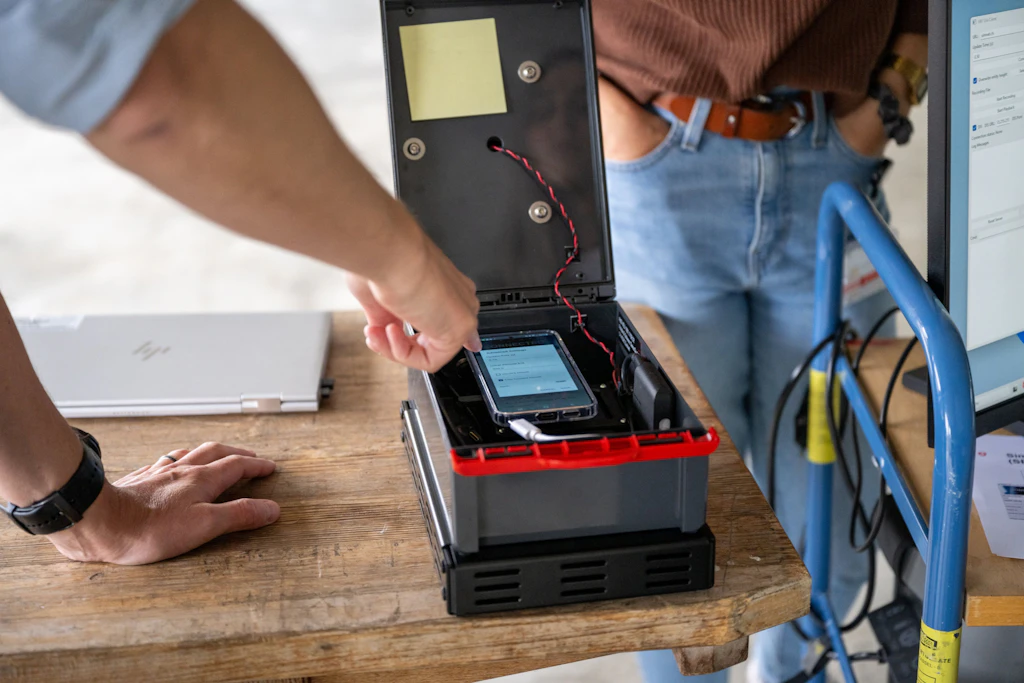 Boîtier ouvert contenant des composants électro-niques intégrés et un smartphone, utilisé pour établir une liaison entre une cible réelle et l’environnement de simulation.