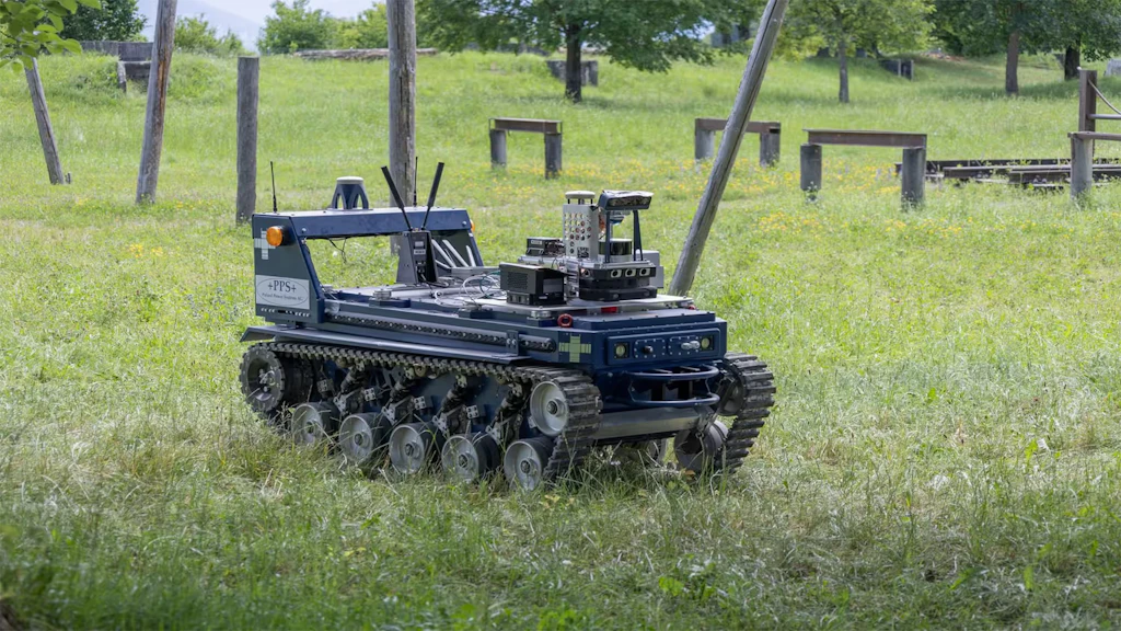 Fotografia del sistema robotico: un robot blu con cingoli in un parco erboso.