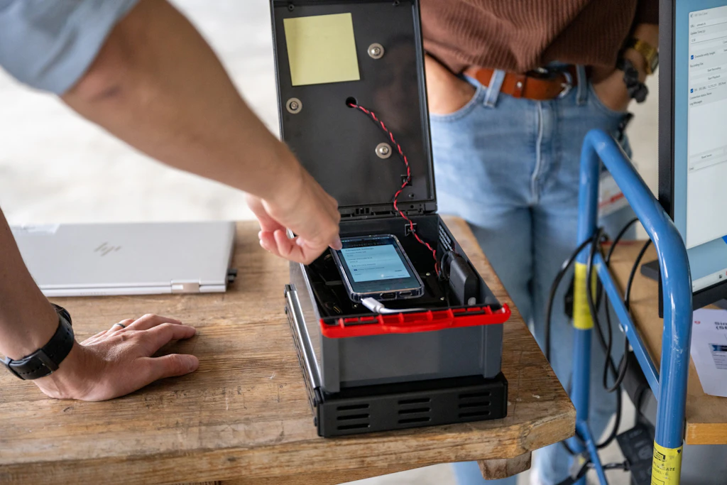 Scatola aperta con componenti elettronici integrati e uno smartphone, utilizzata per effettuare il collegamento di un bersaglio reale all’ambiente di simulazione.
