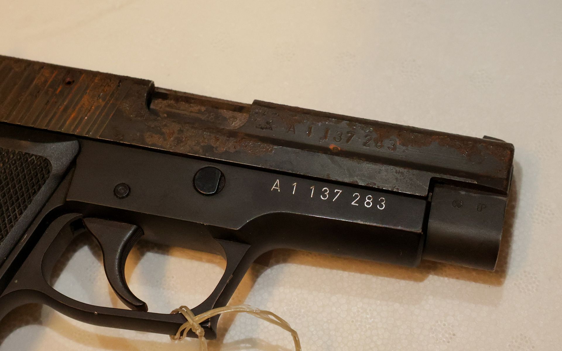 Su un tavolo si trova una pistola. Si vede il numero di serie impresso con il colore.